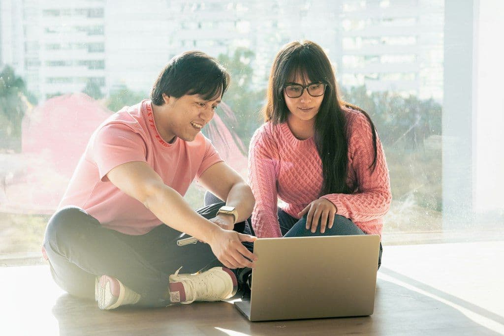 A man and a woman sitting on the floor and choosing gifts together on a laptop